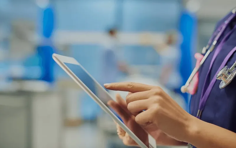 A clinician using a tablet on a hospital ward